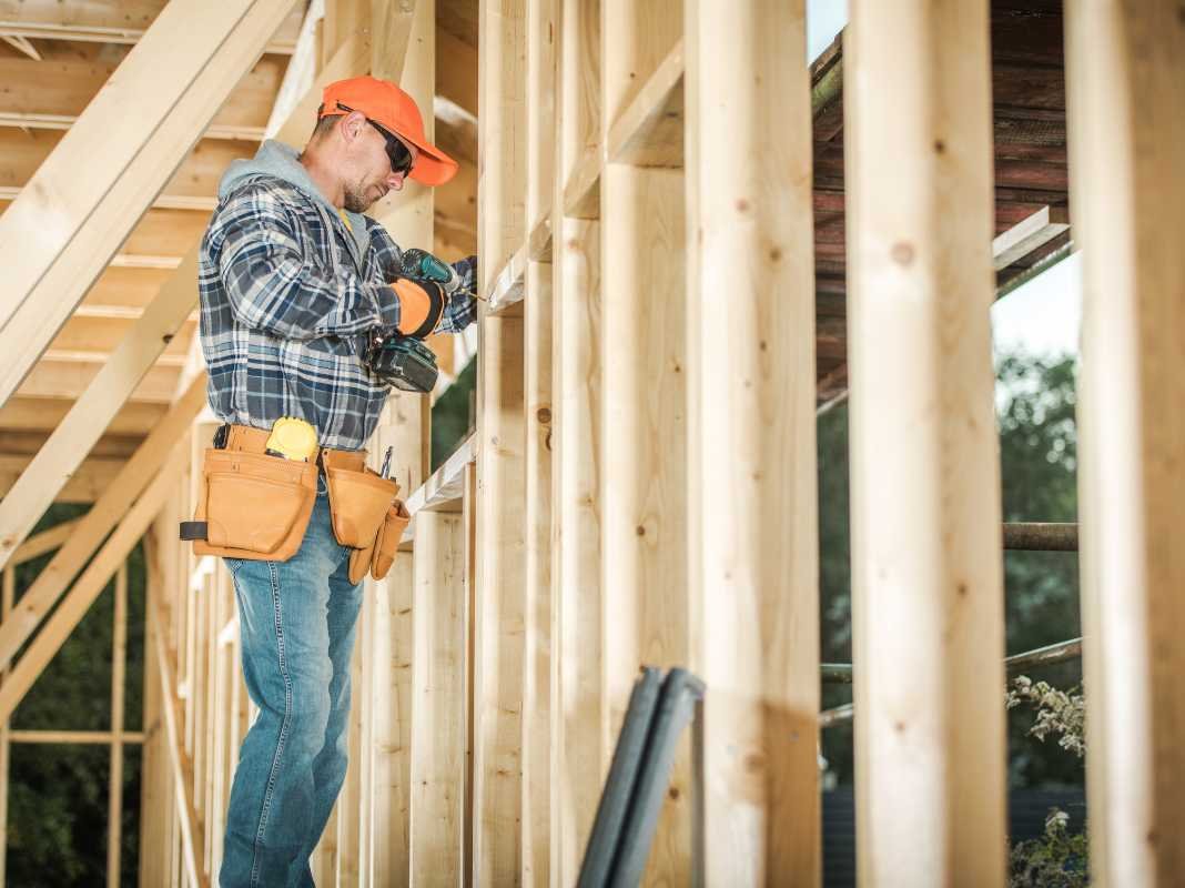 Artisan en train de visser une ossature bois sur un chantier
